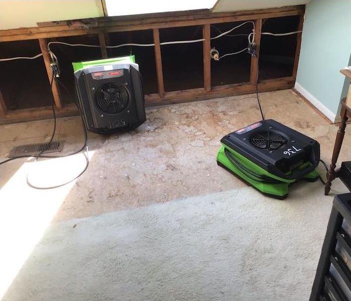 Room with exposed wall framework and SERVPRO drying equipment on subfloor